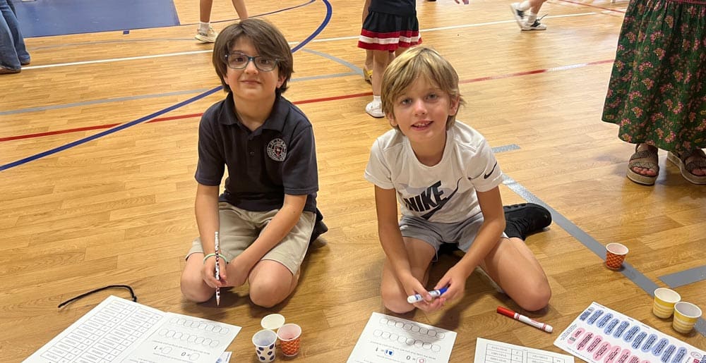 Two boys sitting on the gym floor doing a math project at St Luke's Singapore Math Night