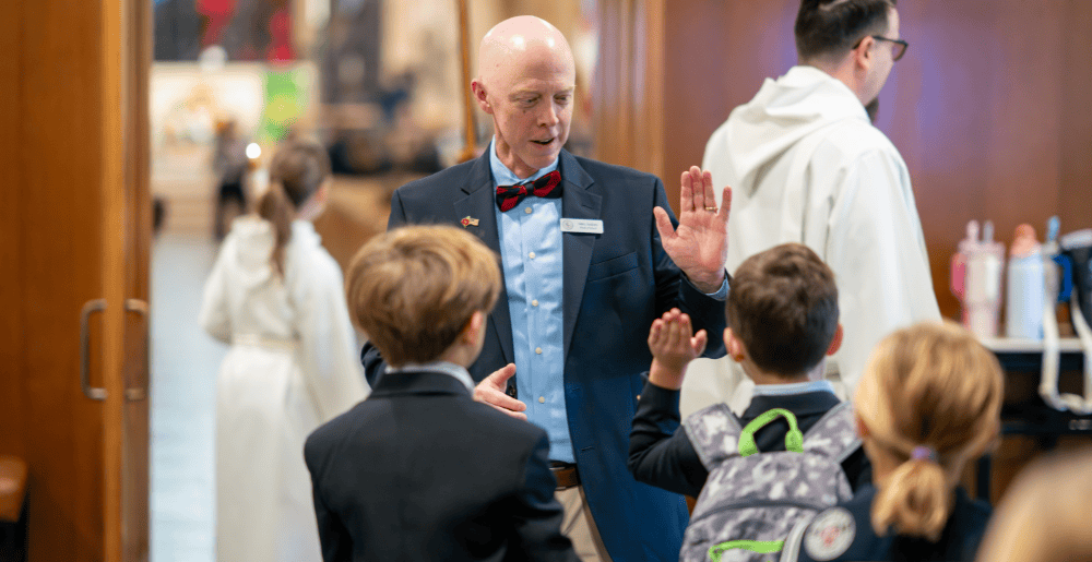 Head of School high-fiving boys on the way to Chapel